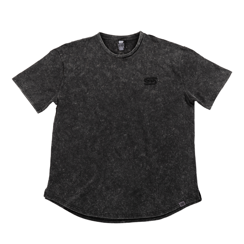 Close-up of black stonewash fabric with a gray tag featuring a black stylized "GS" logo near the hem.